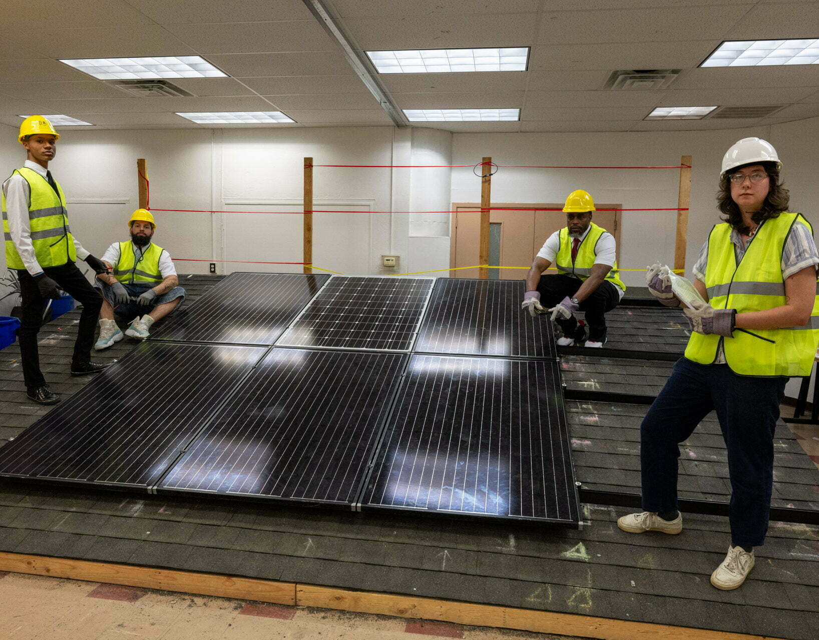 Solar energy students in reflectors learn in front of solar panels in North Philly at OIC