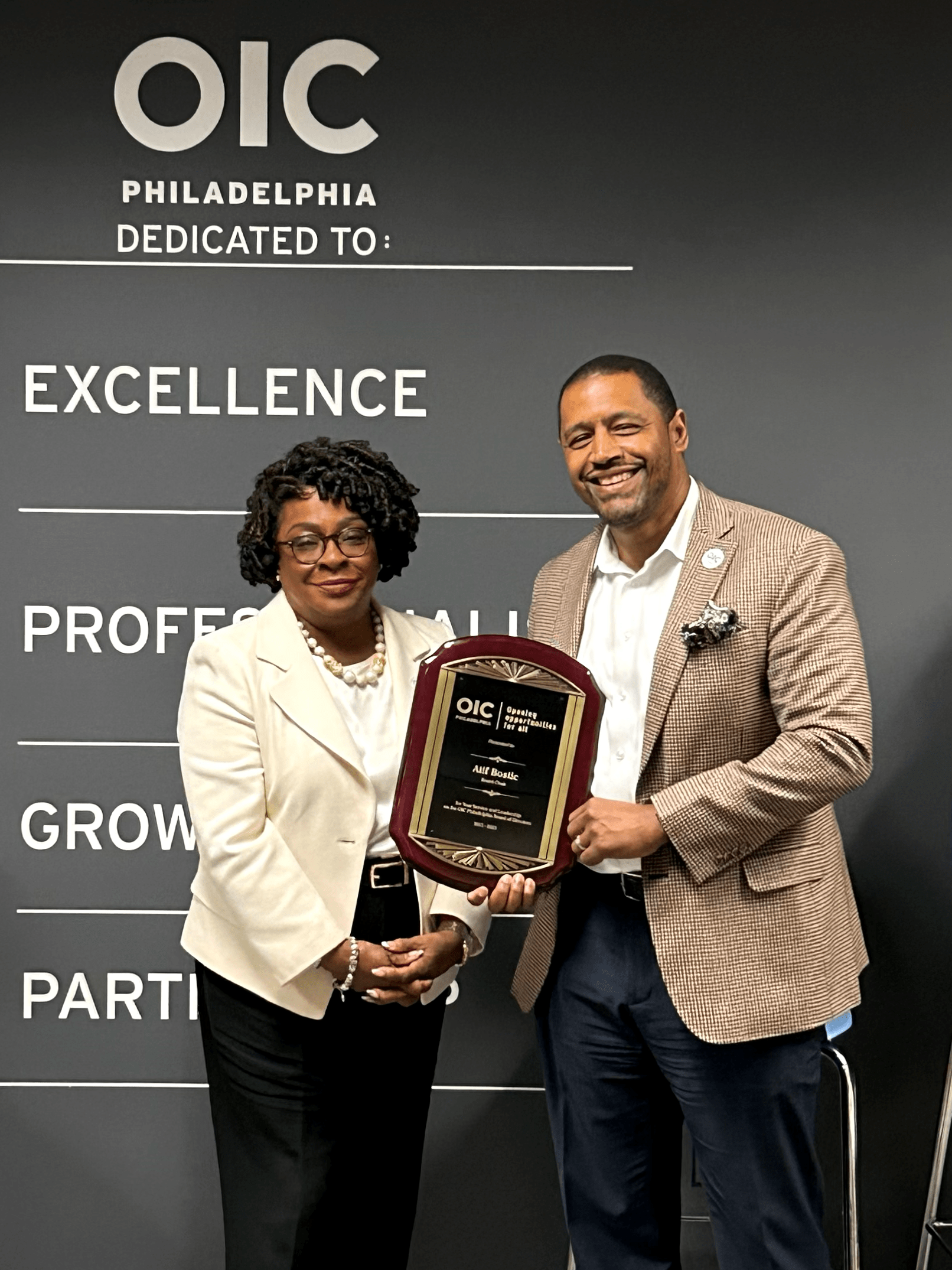 Sheila Ireland hands Atif Botsic award for 10 yrs of service in front of OIC's values of Excellence, Professionalism, Growth, and Partnership