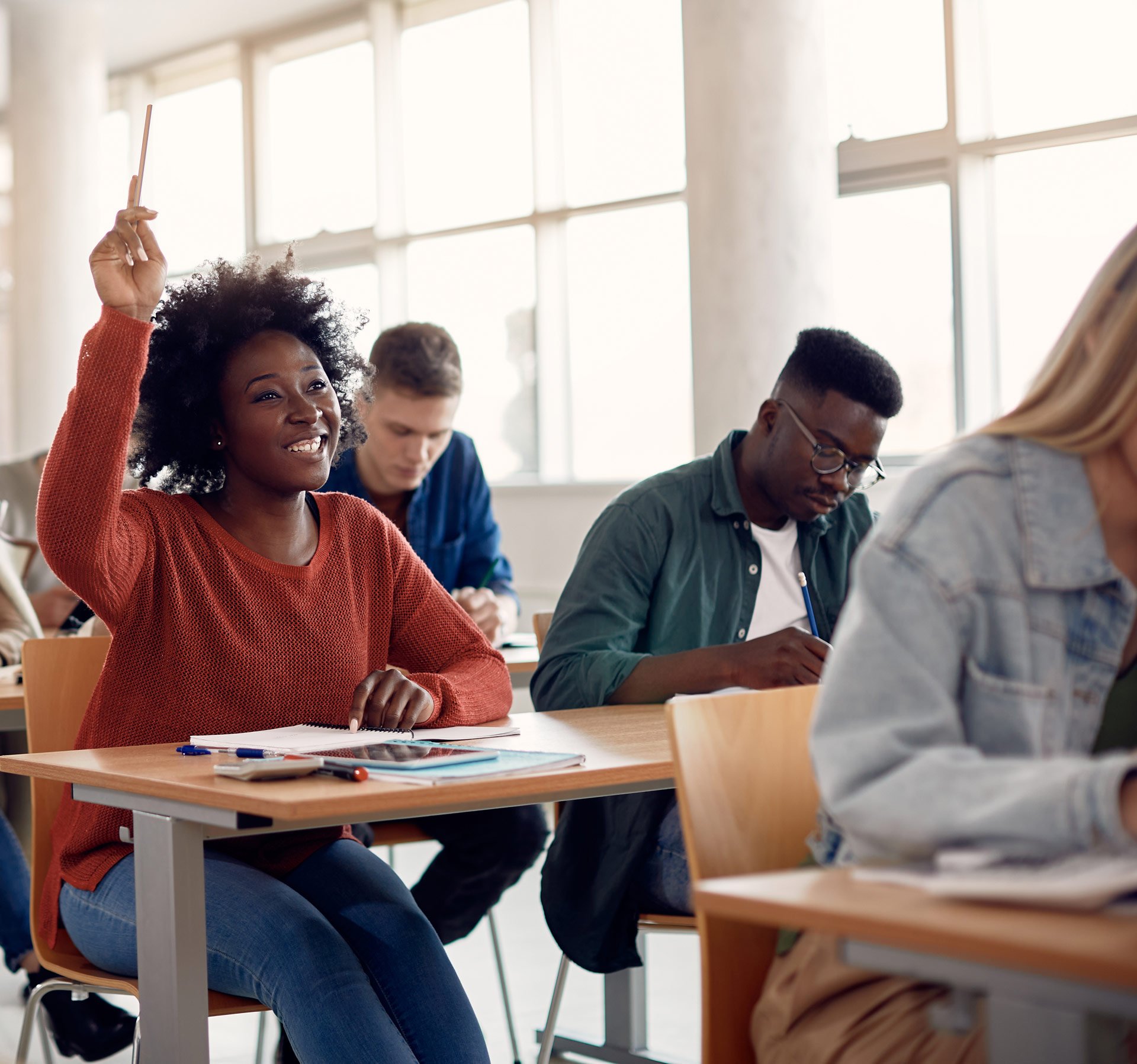 Happy African American woman raising her hand in class.